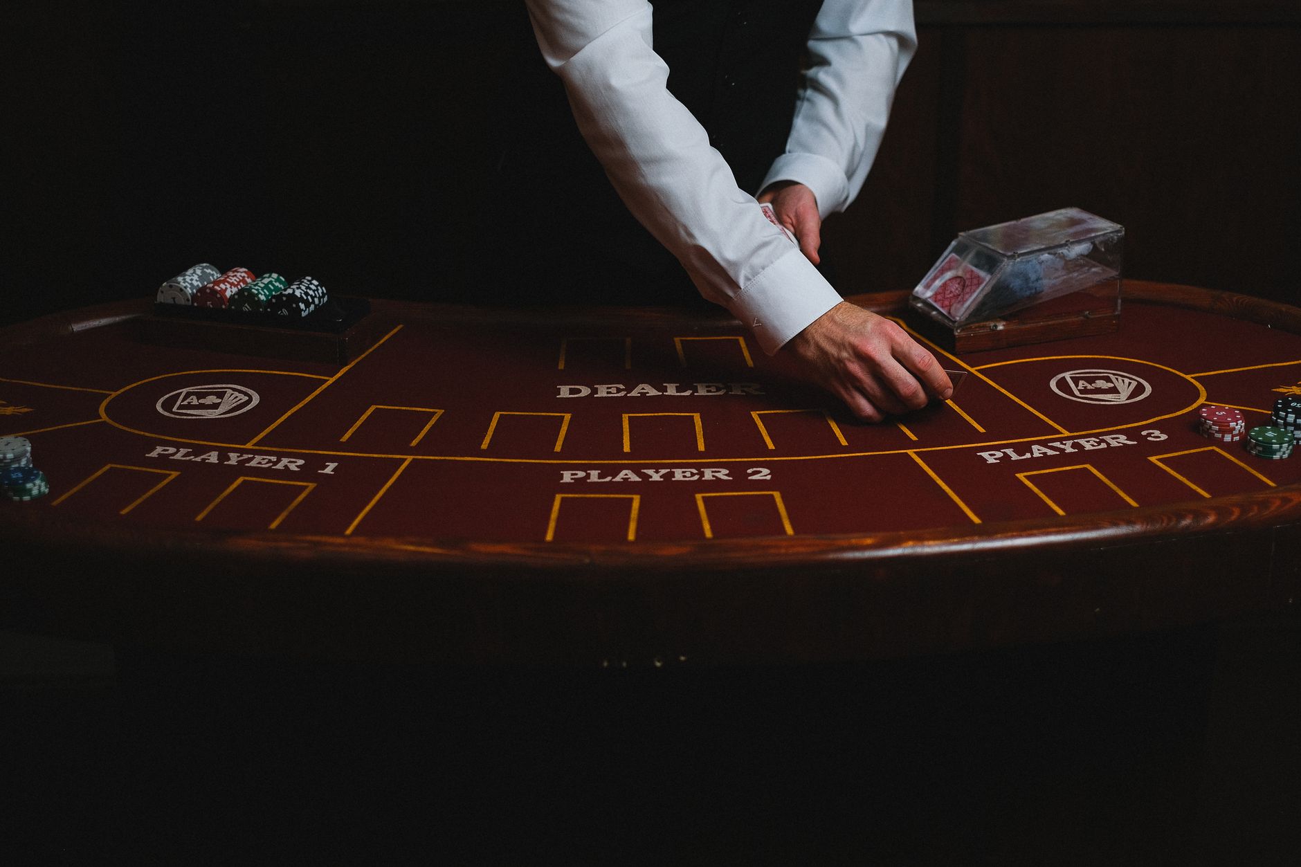 A croupier deals cards on a dimly lit casino table, showcasing gambling atmosphere. — The Evolution of Live Dealer Games in O